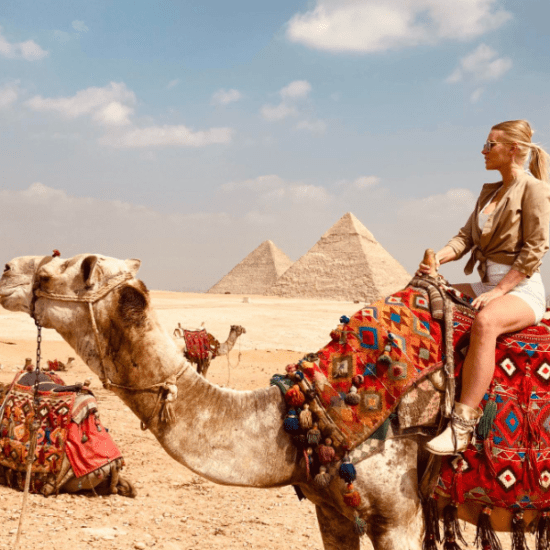 Camel Ride Tour in Cairo at Giza Pyramids - Tourist on camel in front of Giza Pyramids