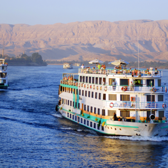 5 Days Nile River Cruise from El Gouna - A scenic view of the Nile River with a cruise ship sailing through it.